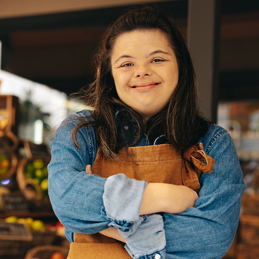 Young woman with disability smiling at camera from workplace