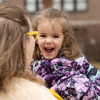 Toddler with Autism laughing in arms of her mother