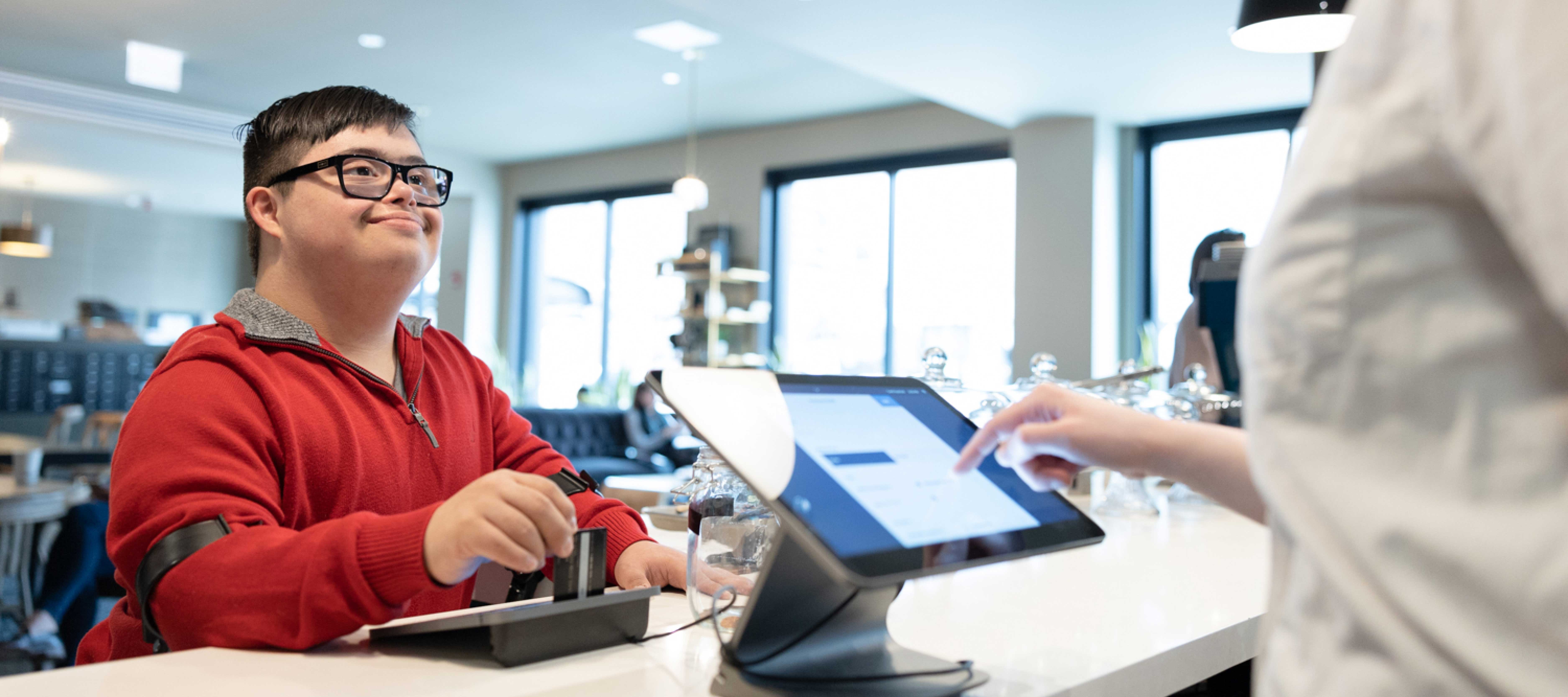 Young man with Down syndrome making purchase with debit card