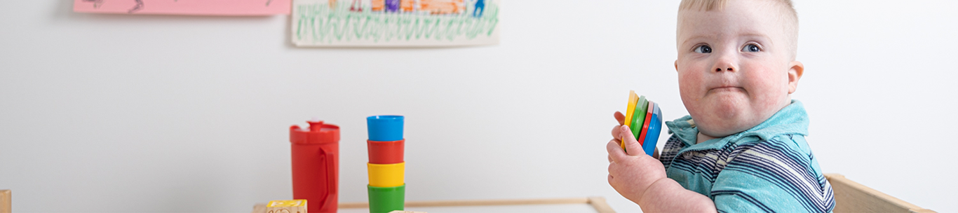 Toddler with Down syndrome sitting at table playing with blocks