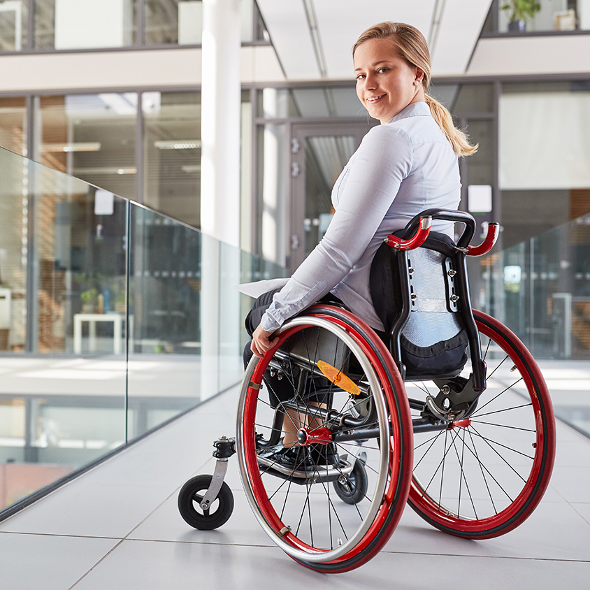 Woman in manual wheelchair at work smiling at camera